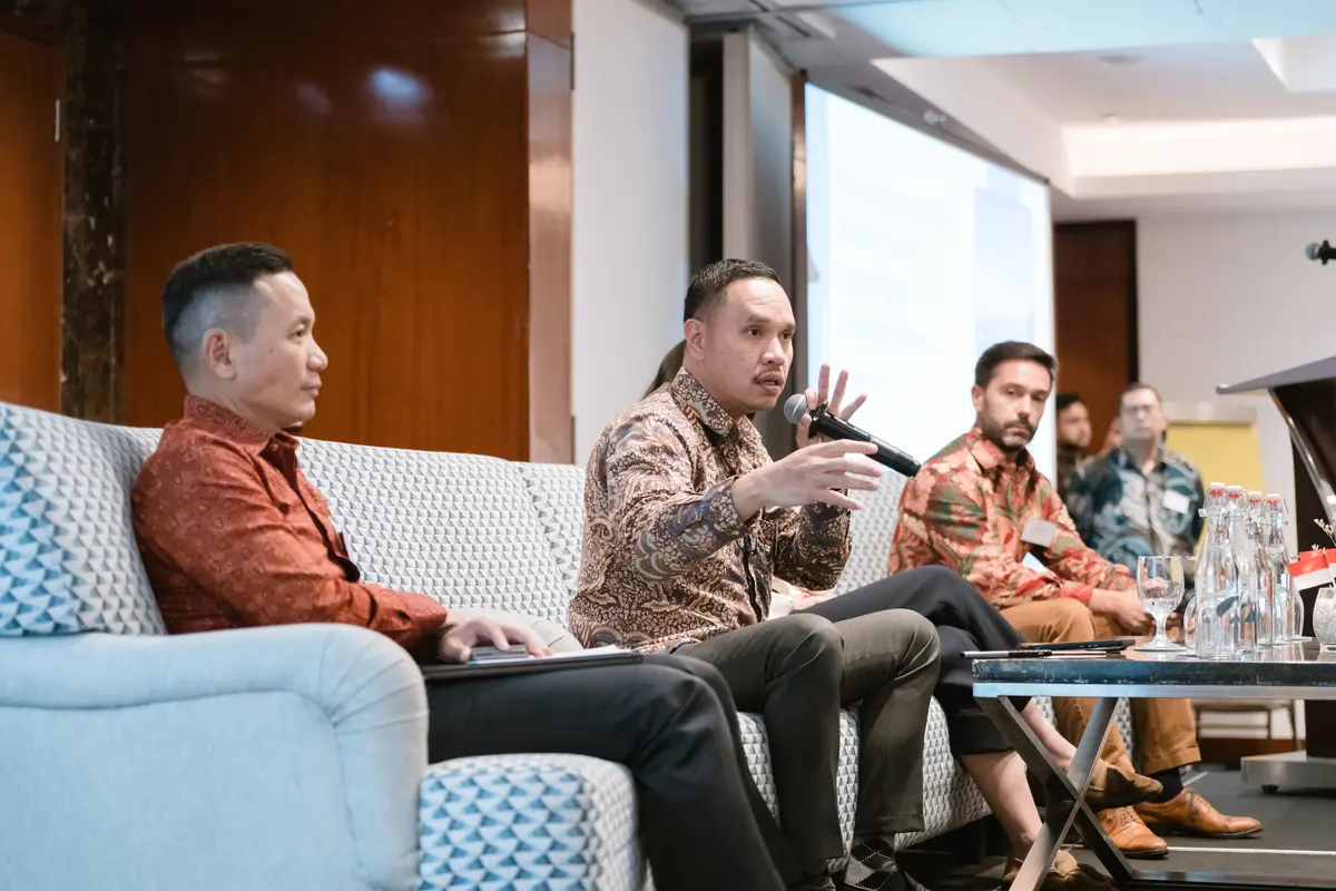 Men on stage and an expert presenting at FIRST workshop attendees in Jakarta