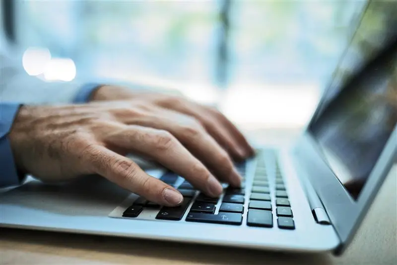 hands typing on keyboard of laptop