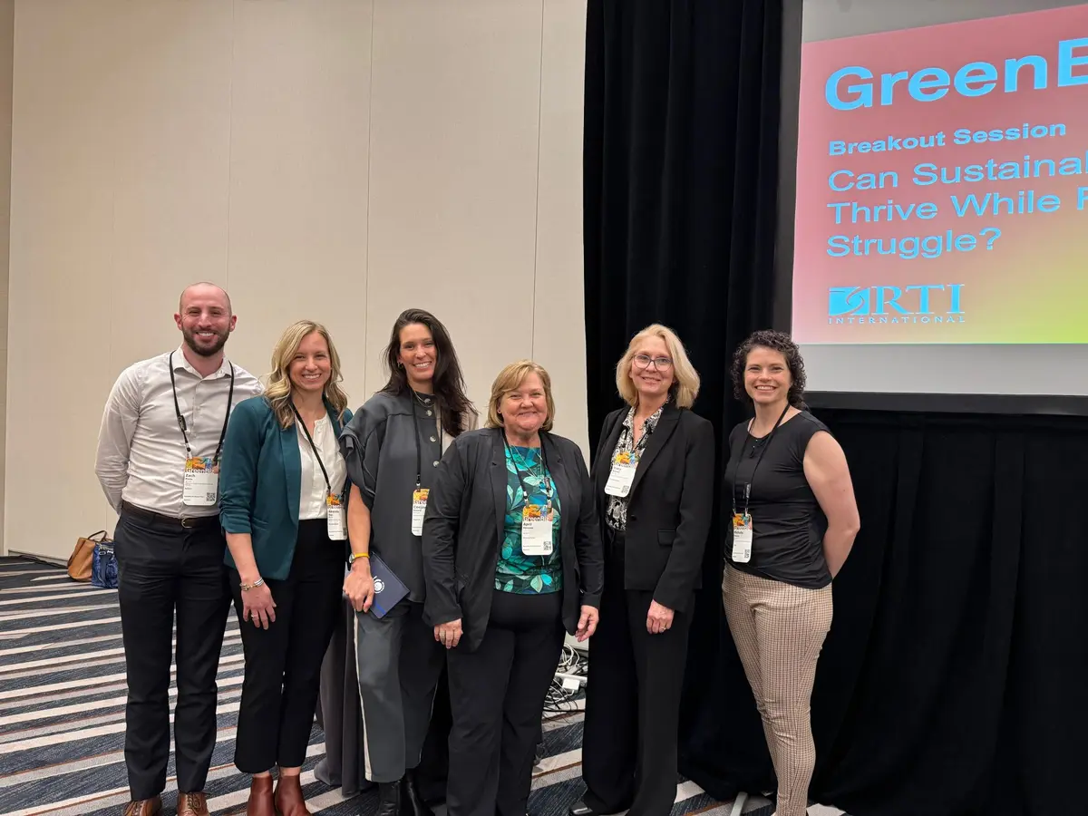 People gathered at the front of a conference presentation room 