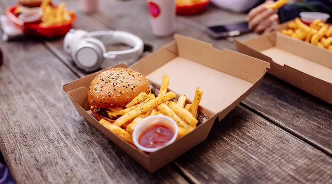 Cheeseburger, french fries, and ketchup in a cardboard to-go box