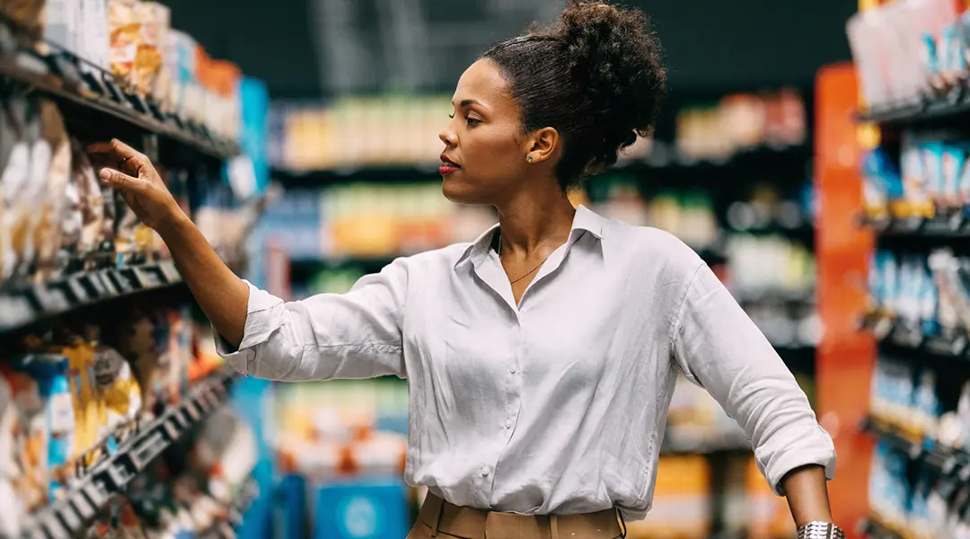 A woman selects food in a grocery store.