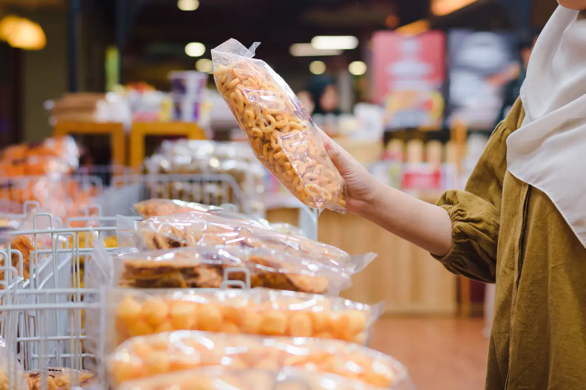  Close Up of Woman Hand Holding Traditional Snack in Plastic Packaging at Store.