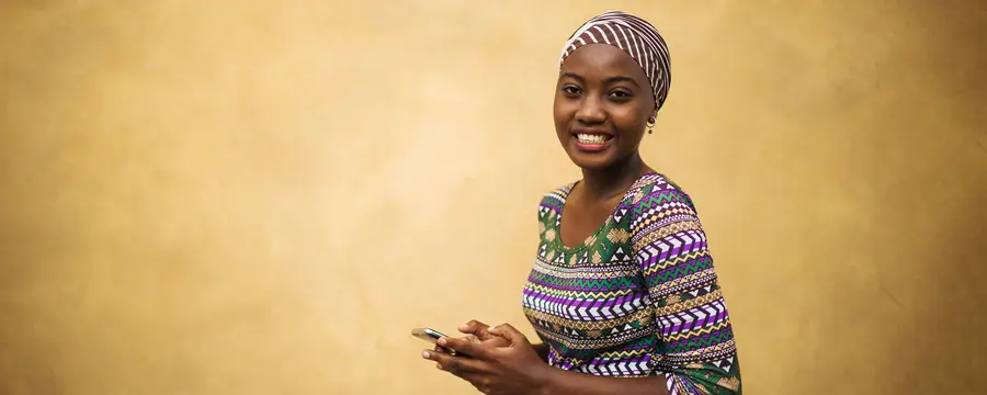 A young African woman reads text messages on a mobile phone.