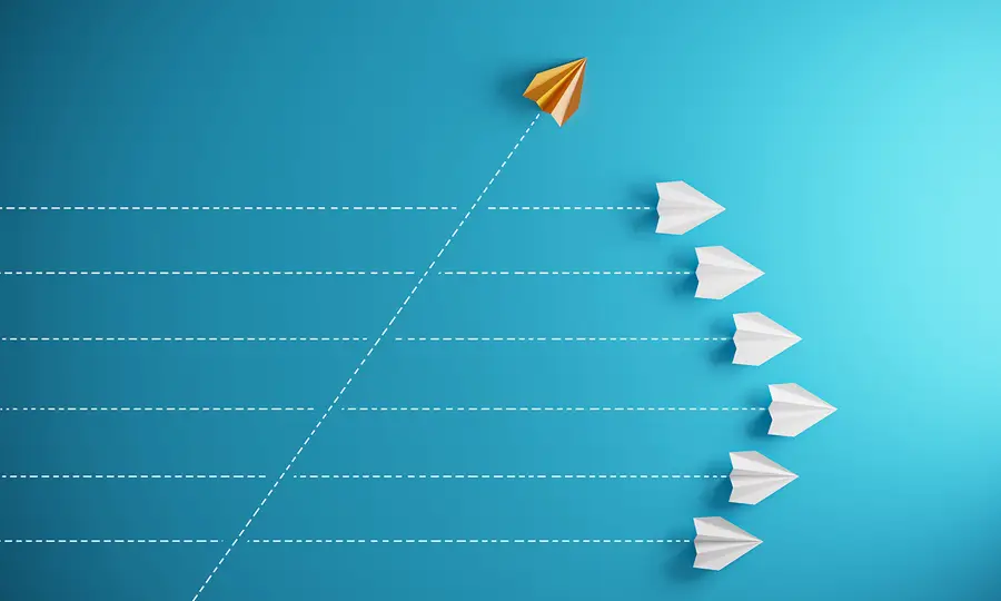 An illustration of an orange paper airplane accelerating ahead of a group of other paper airplanes.