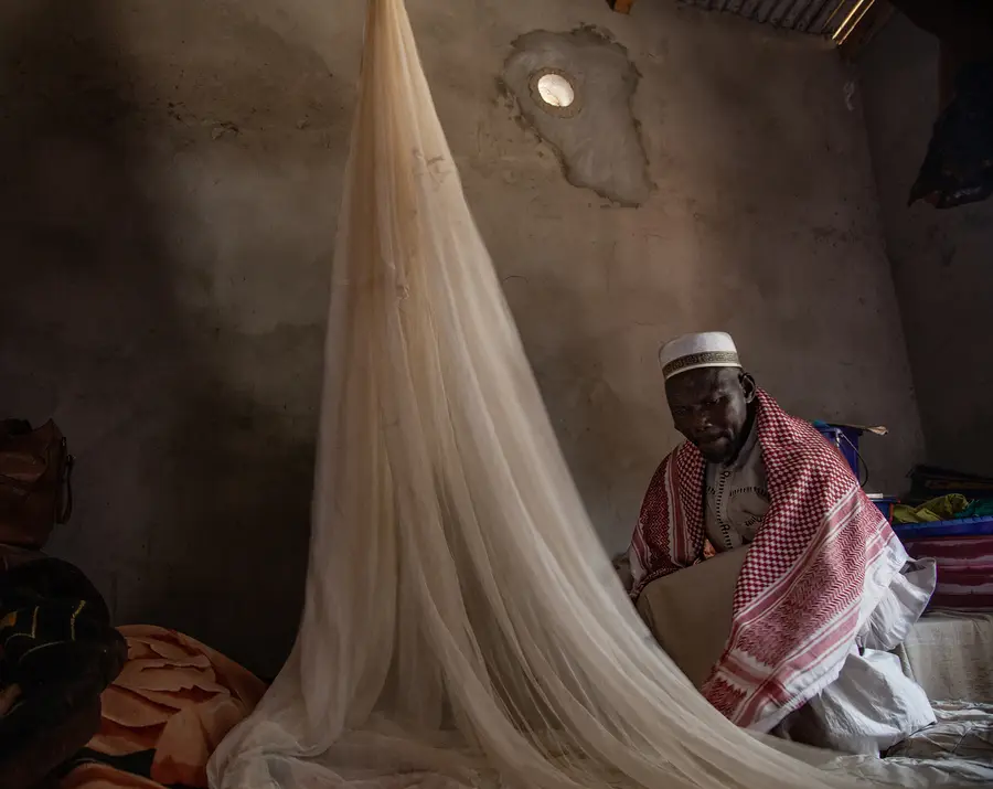 Imam Kerfalla Camara hangs the bed net he received through the mass bed net distribution campaign led by USAID StopPalu+. 