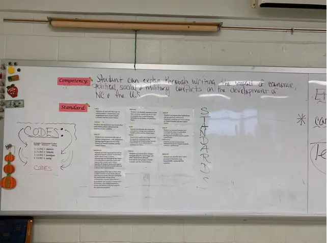 A teacher’s whiteboards displaying competencies and standards at Carroll Magnet Middle School.