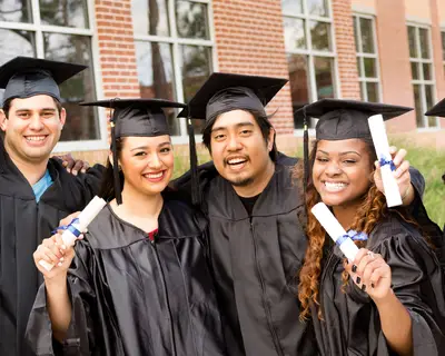 Graduates in caps and gowns hold their diplomas