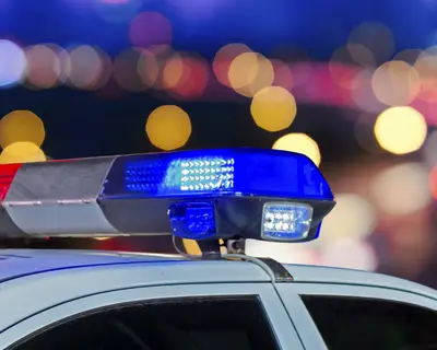 Lights on top of a police car with city lights in the background
