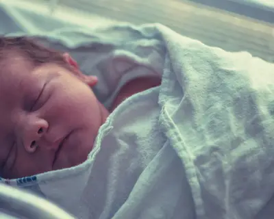 A newborn baby sleeps in a hospital crib