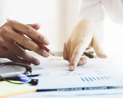 A closeup of two researchers working with charts and graphs at a desk.