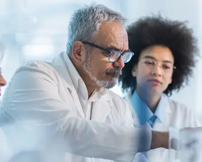 A team of biotechnology experts gather around a desktop computer.