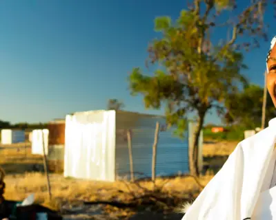 A female South African health worker stands outdoors.