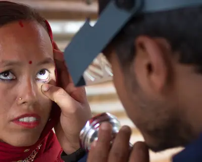 A health worker checks a woman's eyes for signs of trachoma.