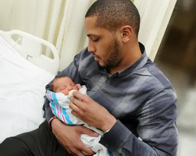 A father holds a newborn baby in a hospital room