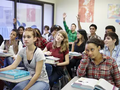 High school students raise their hands to participate in class.