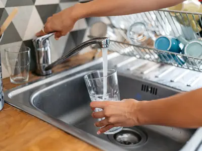 Person fills glass cup with tap water