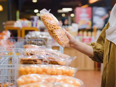  Close Up of Woman Hand Holding Traditional Snack in Plastic Packaging at Store.