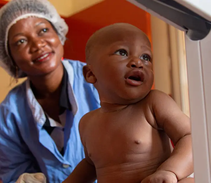 Baby being weighed on scale with medical team and mother