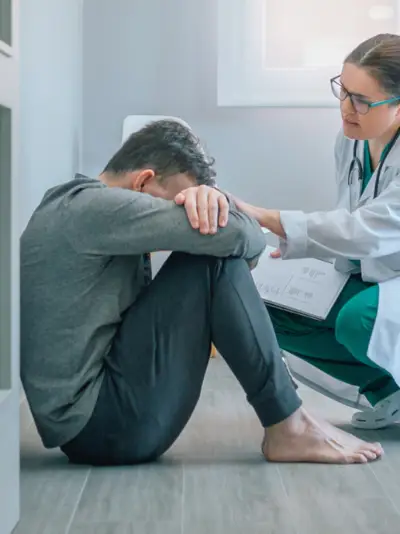 Man sitting against door with a doctor touching his arm.