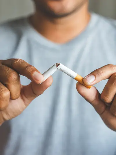 A closeup of a man breaking a cigarette in half.