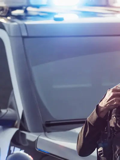A male and female officer are standing outside a police car talking