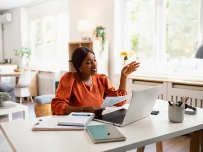 Photo of a smiling Black woman having a virtual meeting on a laptop