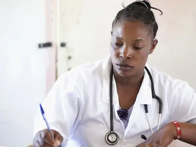 Kenyan doctor updates patient notes in her office