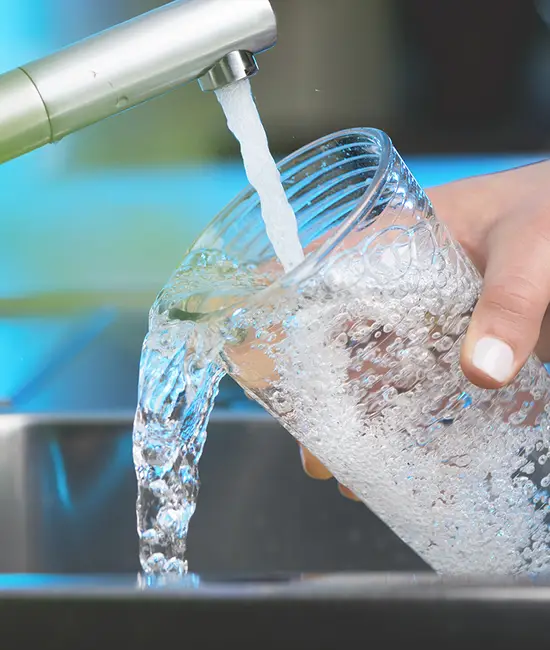 Closeup of someone filling a glass of water from a faucet.