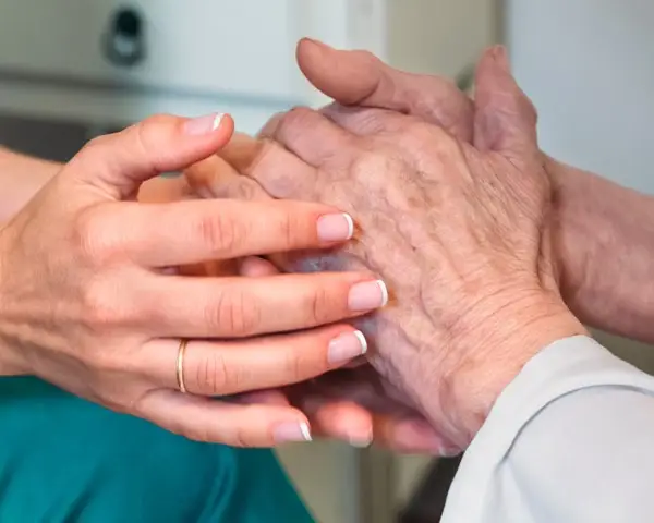 nurse holding elderly hands in comfort