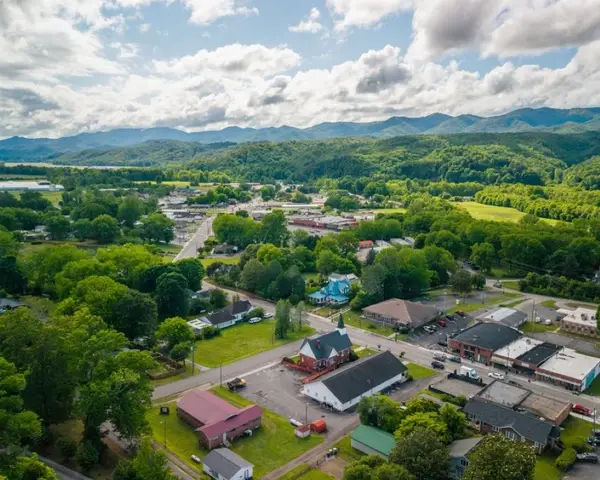 An aerial view of Andrews, North Carolina, showing houses and businesses, forests and farmland, and mountains in the distance.