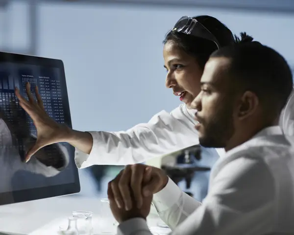 Photo of two individuals looking at a computer screen.