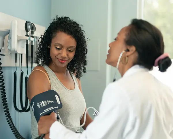 An African-American woman has her blood pressure checked by a female doctor.
