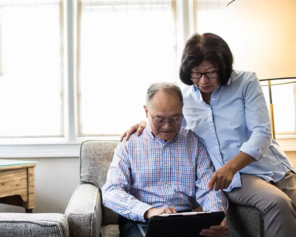 A senior Asian man and woman read news together on a tablet.