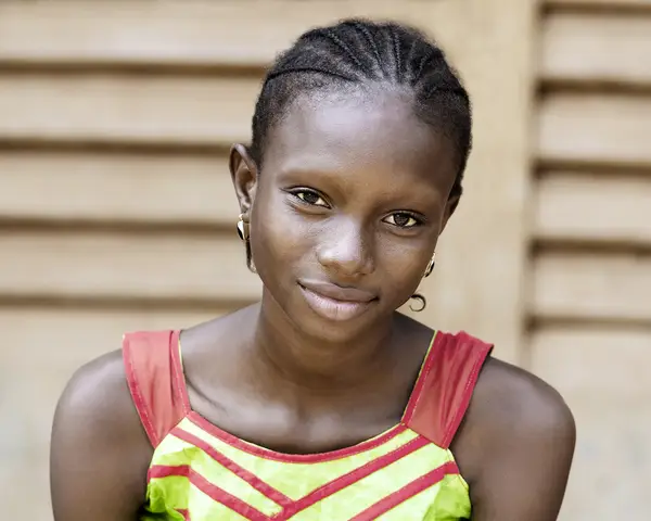 A teenage girl from Africa smiles at the camera.