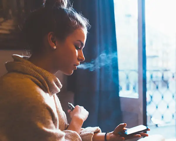 Teen vaping while using mobile phone