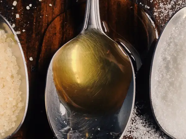 A spoon of raw sugar, a spoon of honey, and a spoon of cane sugar