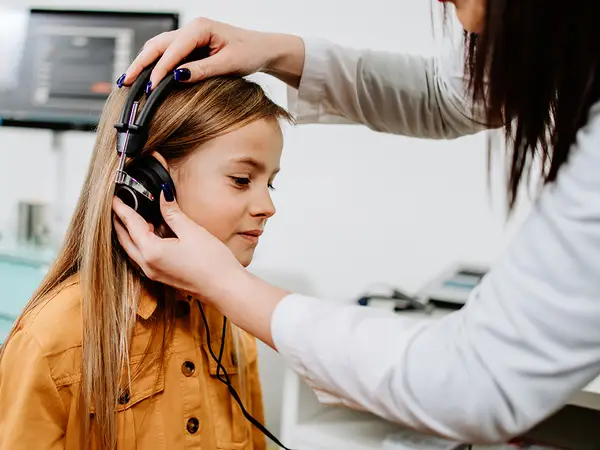 A middle-school girl gets a hearing test from an audiologist.