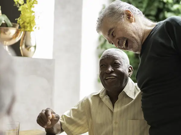 A group of senior men talk and socialize at an outdoor table.