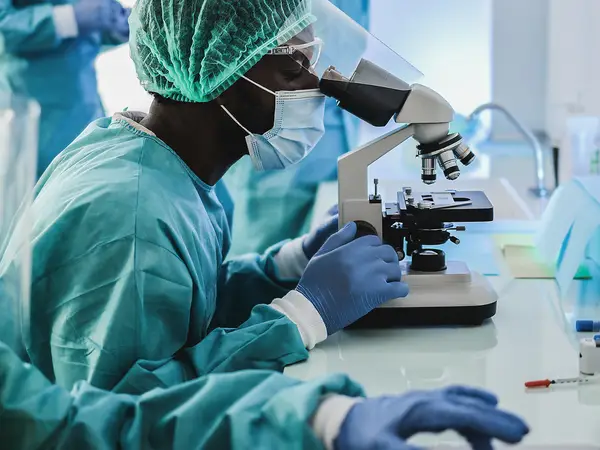 Scientists wearing protective gear study microbes.