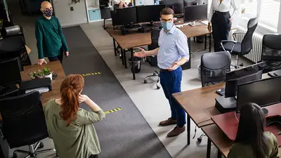 Workers use masks and social distancing while sharing office space during a pandemic.