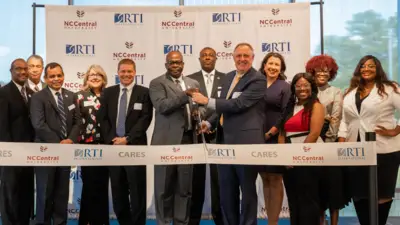 A group of people participate in a ribbon-cutting ceremony for NC Central University.