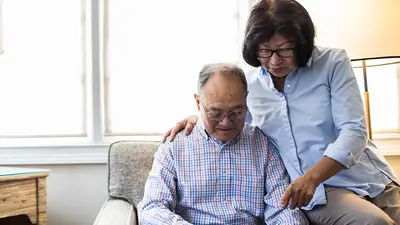 A senior Asian man and woman read news together on a tablet.